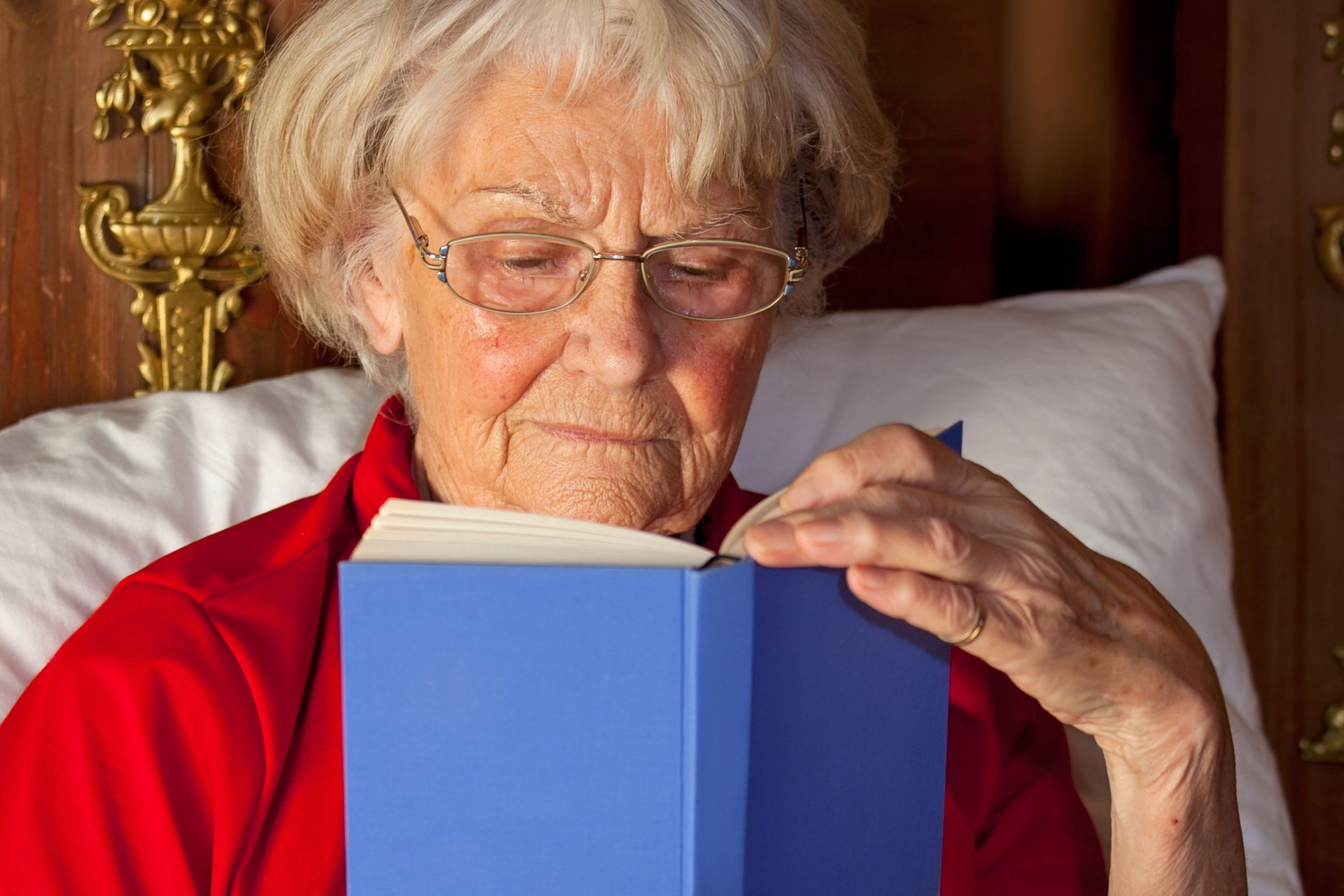 Bedridden elderly woman reading